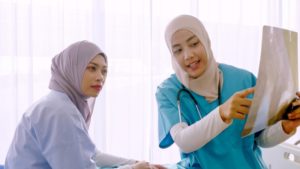 Muslim female doctor explaining chart to patient at hospital ro